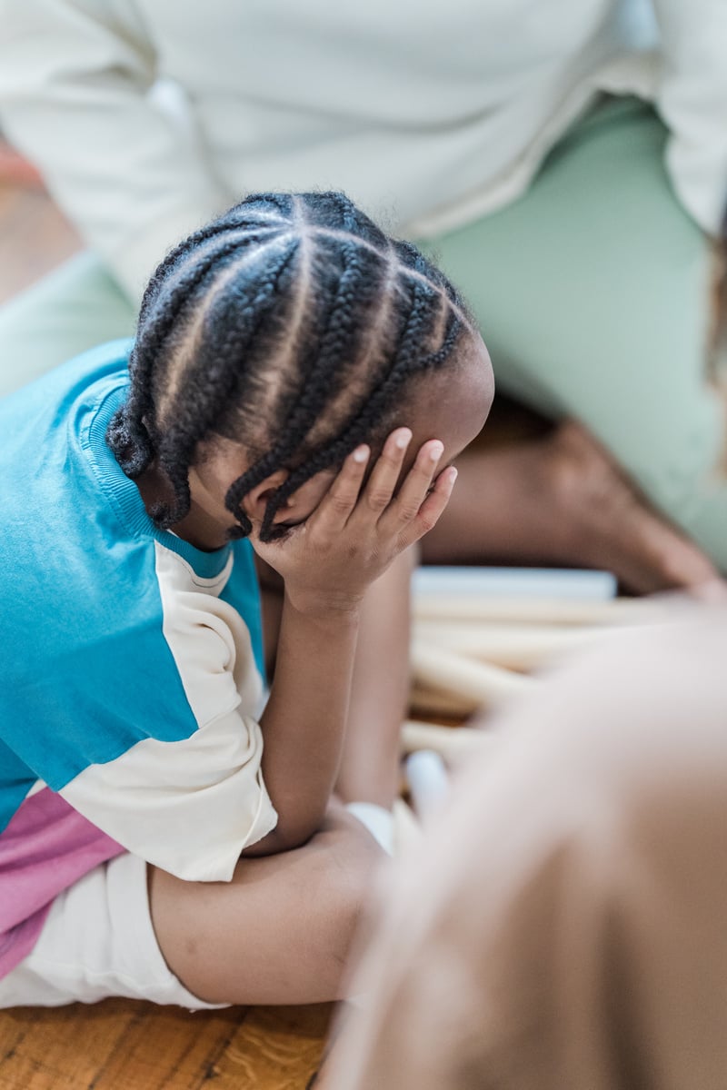 Boy with Cornrows Resting Head in Hand